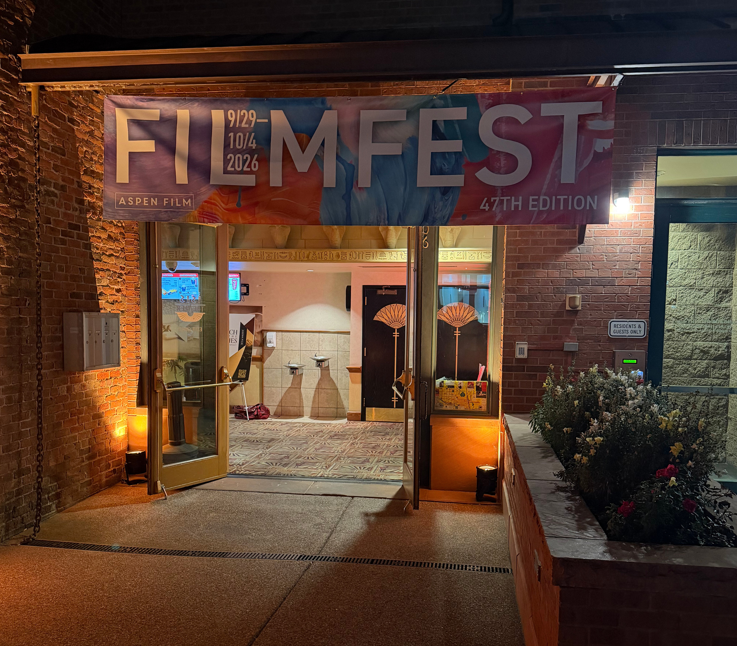 An illuminated theatre entrance beneath a festival banner at night