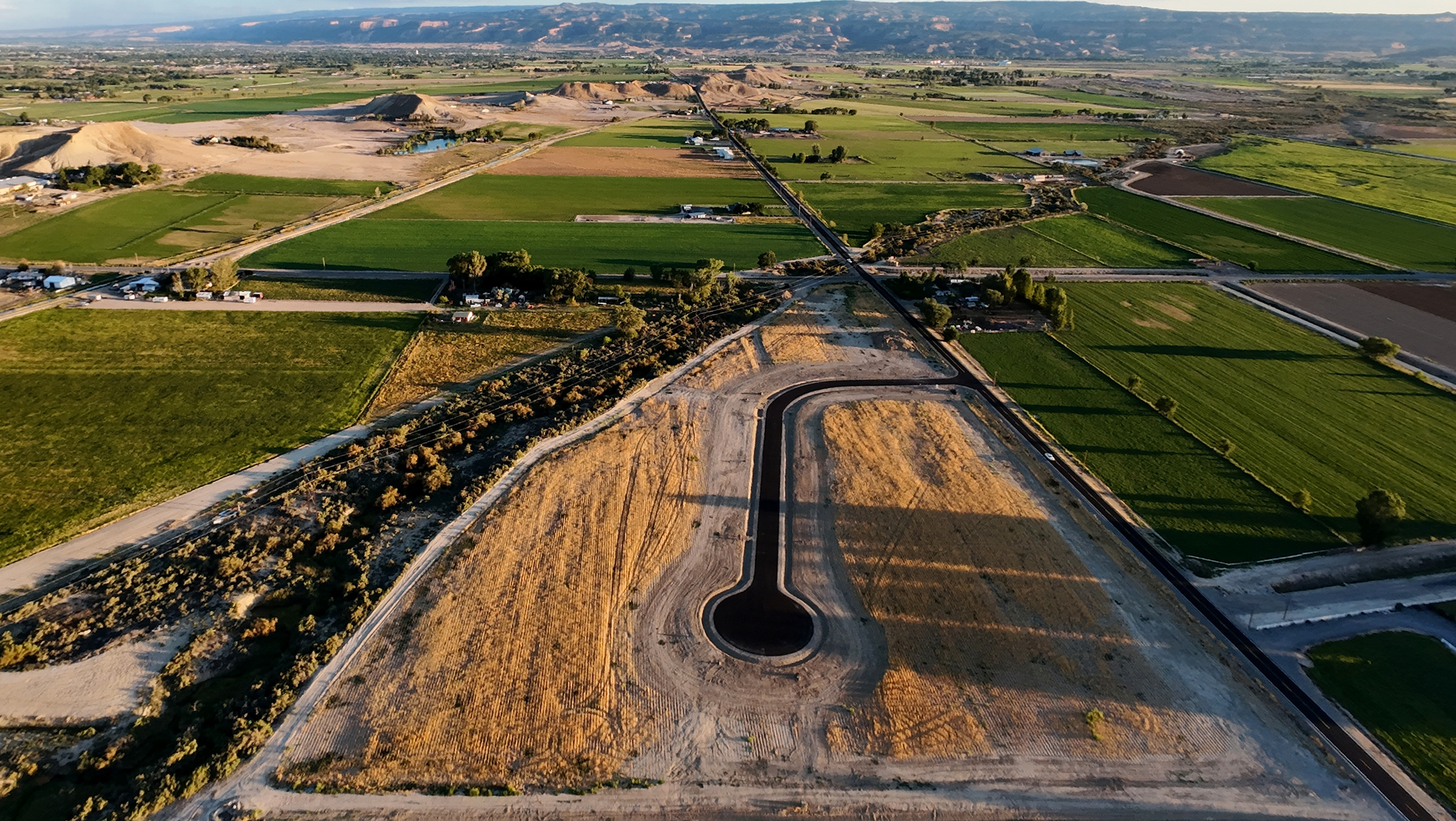 Golden-hour aerial photograph of a development amid Western Colorado farmland