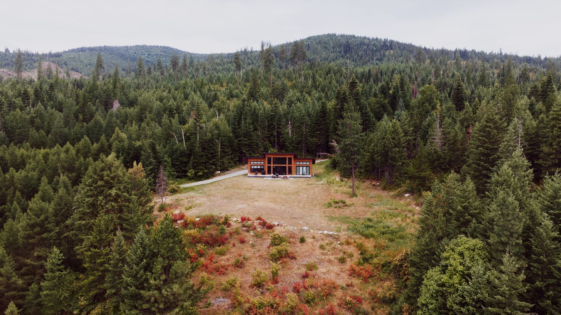 Aerial view of a mountain cabin surrounded by pine forest