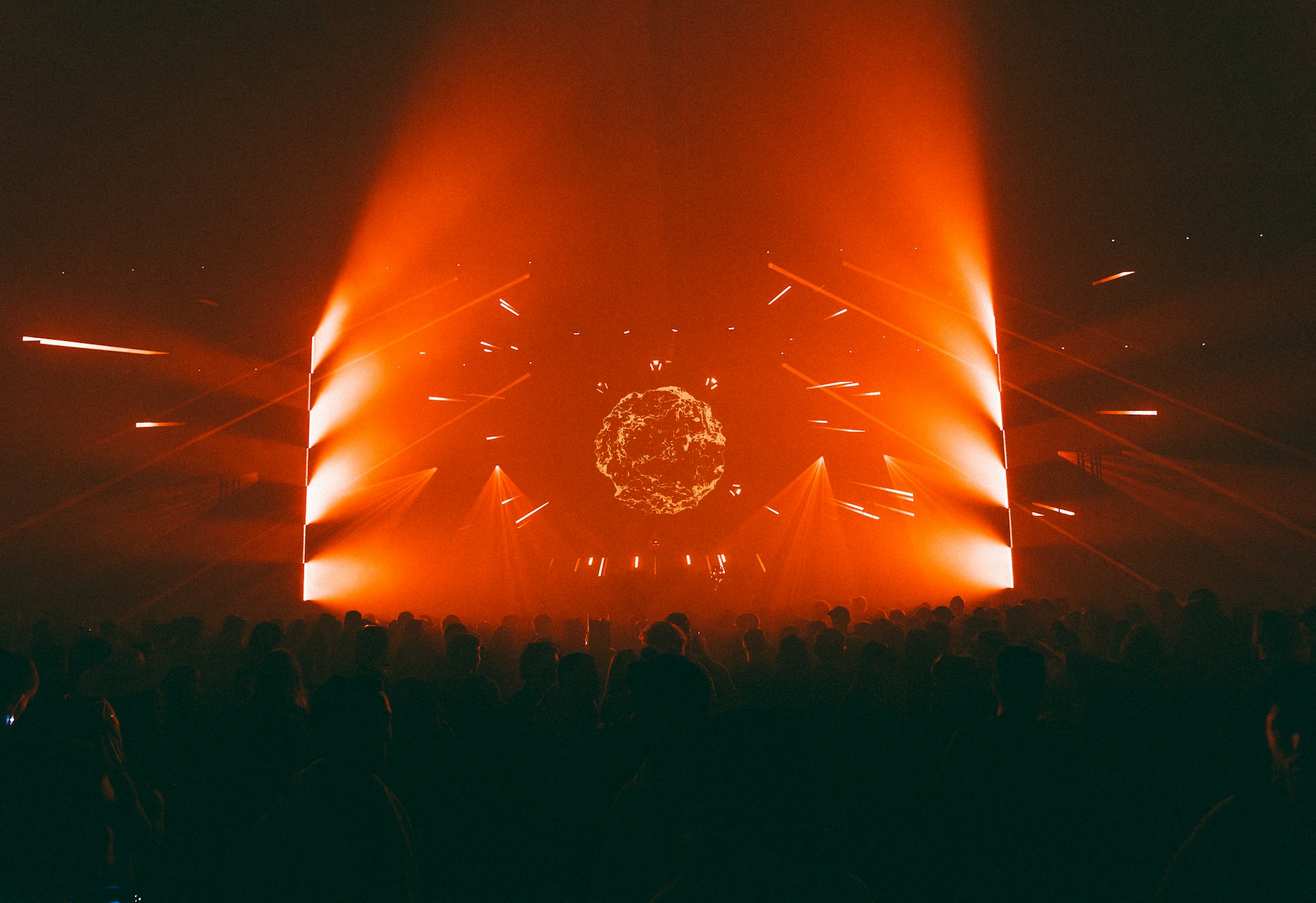 Concert crowd facing an orange illuminated stage
