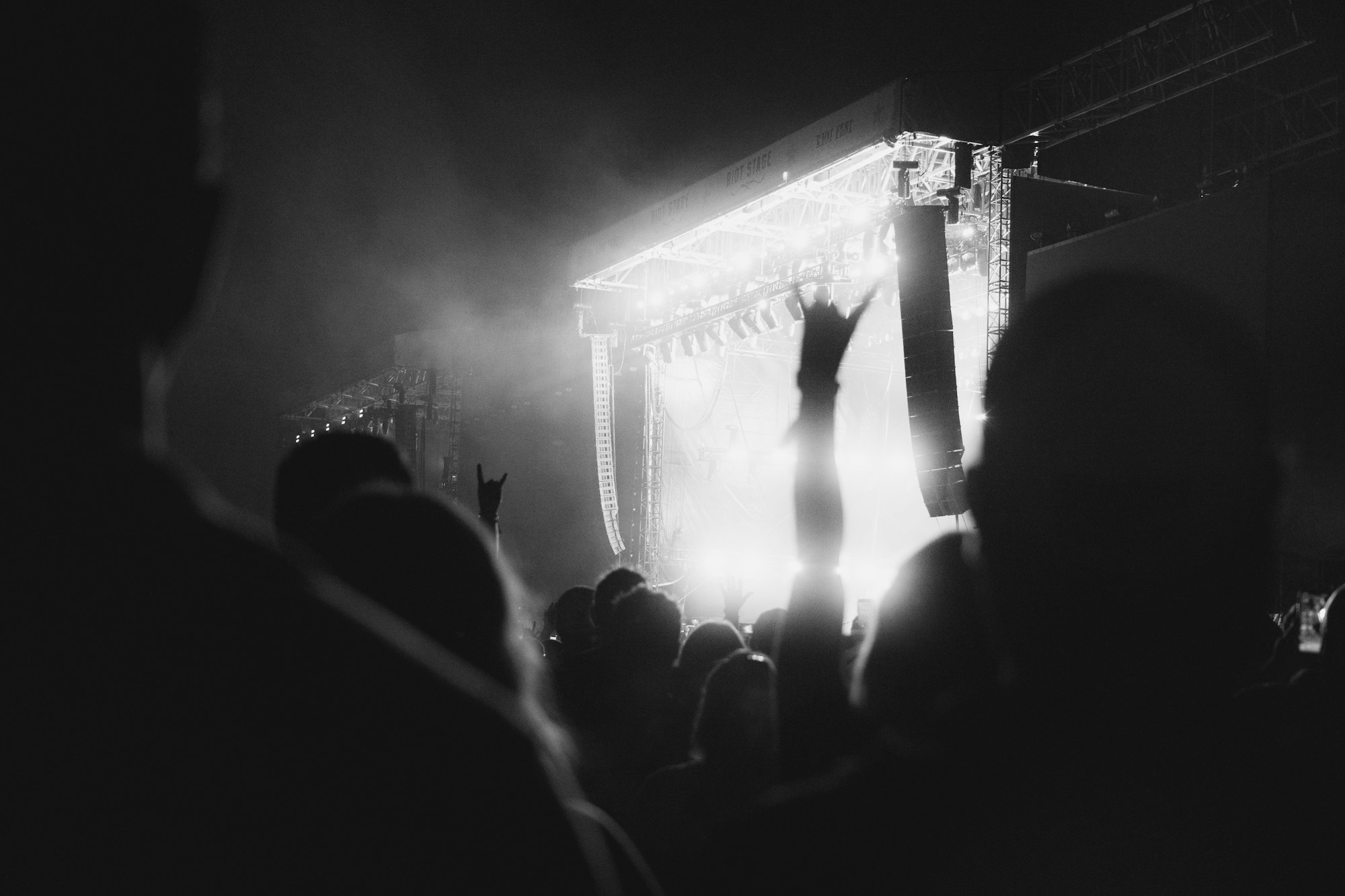 Concert crowd with hands raised beneath stage lights